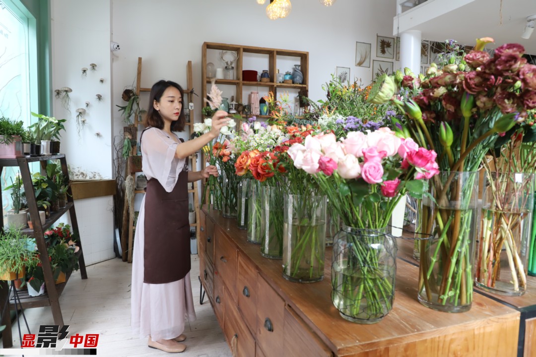 王黎媛是一名河南姑娘，在昆明念完大學(xué)后，就再也舍不下春城的藍天陽光、青山碧水，更舍不下這里的四時繁花，于是就干脆留了下來，成了一名媒體人。2017年的時候又毅然辭去工作，創(chuàng)業(yè)開起了花店，成了都市里的一名“花房姑娘”。圖為王黎媛在自己的花店中整理鮮花。新華網(wǎng) 周亞平/攝 念新洪/文